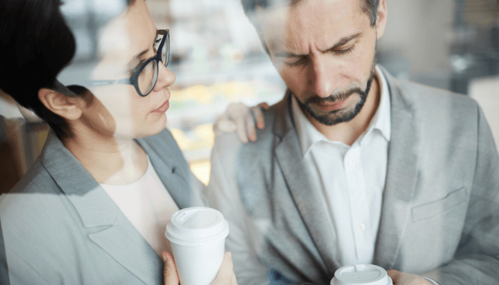 Business Colleagues having coffee deep in conversation, being supportive, with a look of concern.