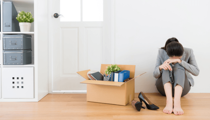 emotionally distraught woman at home with a box of items from her office