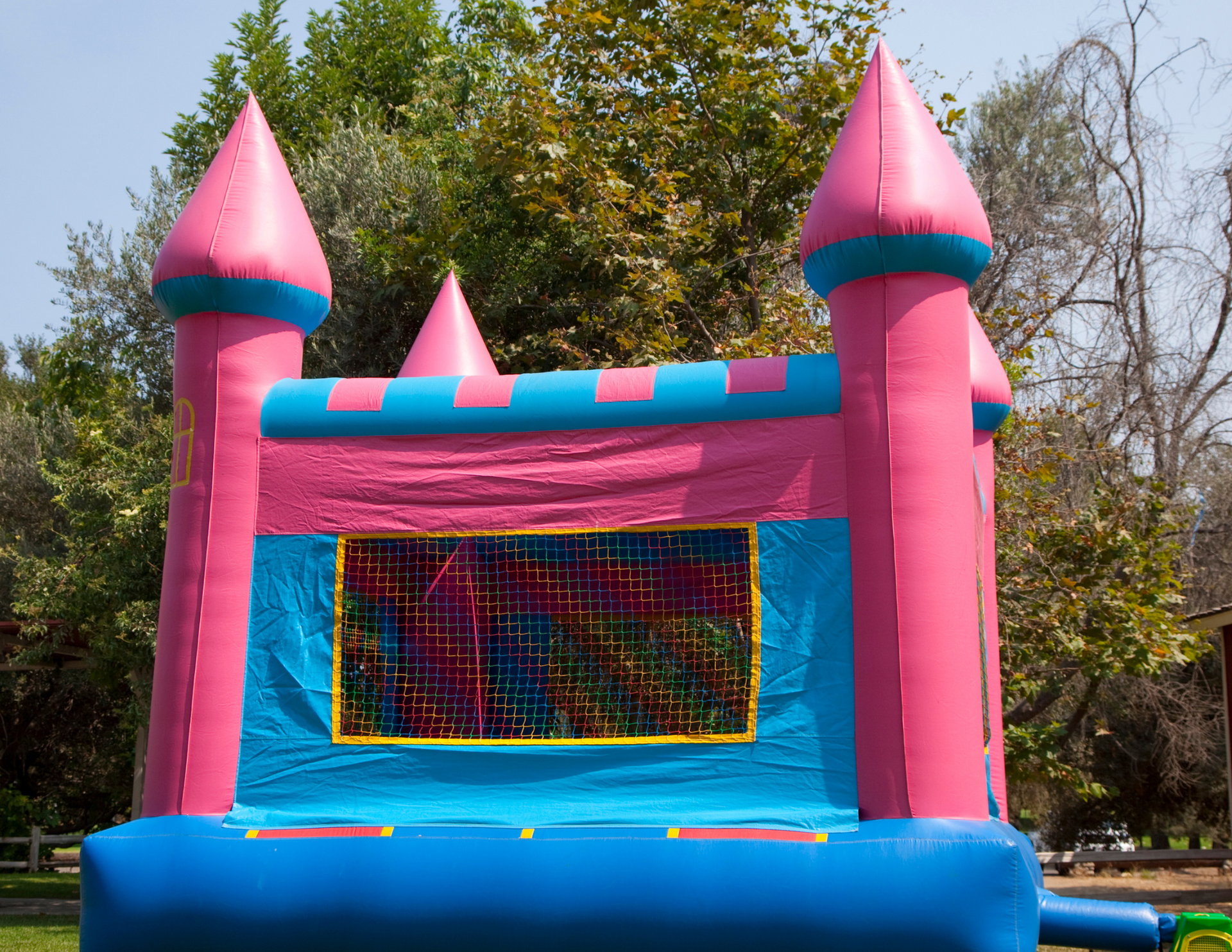 A pink and blue bouncy castle with trees in the background