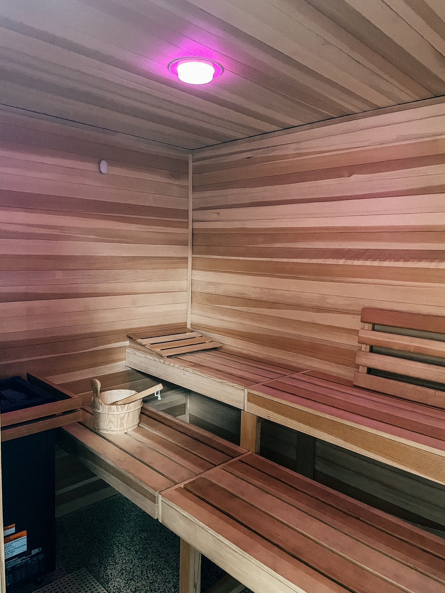 a wooden sauna with a pink light on the ceiling .