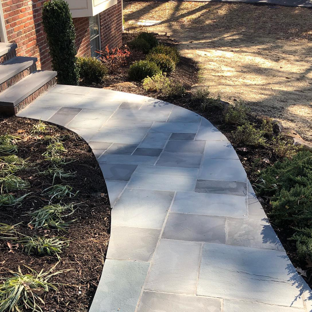 A curved walkway in front of a brick house