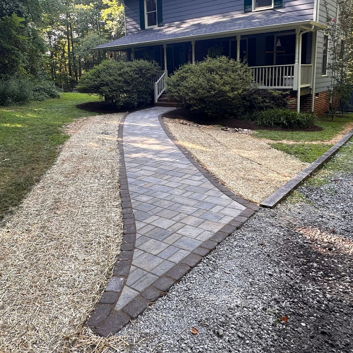A curved walkway in front of a brick house