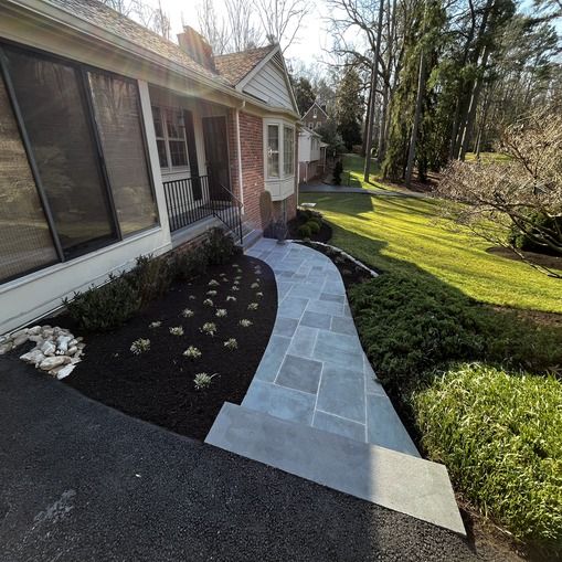 A concrete walkway going through a lush green lawn.