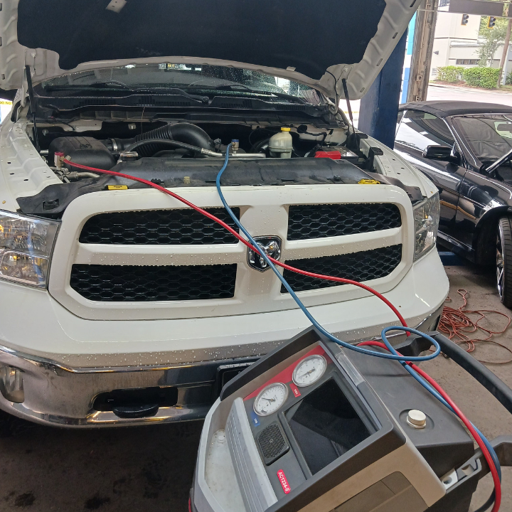 Person holding a red car diagnostic scanner near an open engine bay