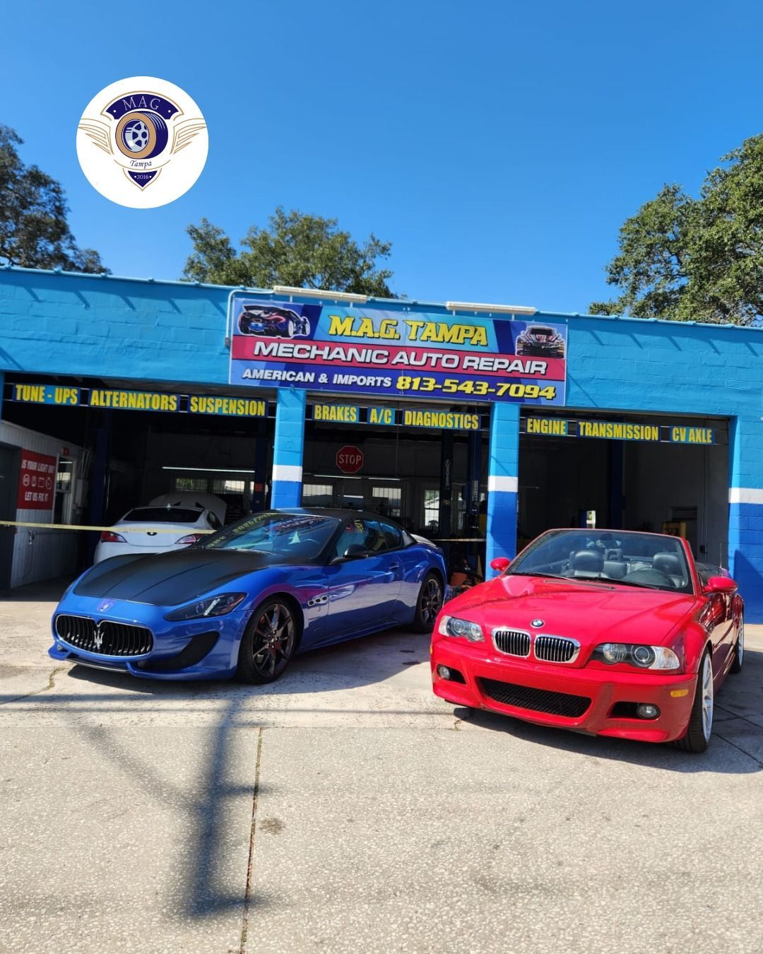 Blue and red BMWs parked outside a bright blue auto shop on a sunny day