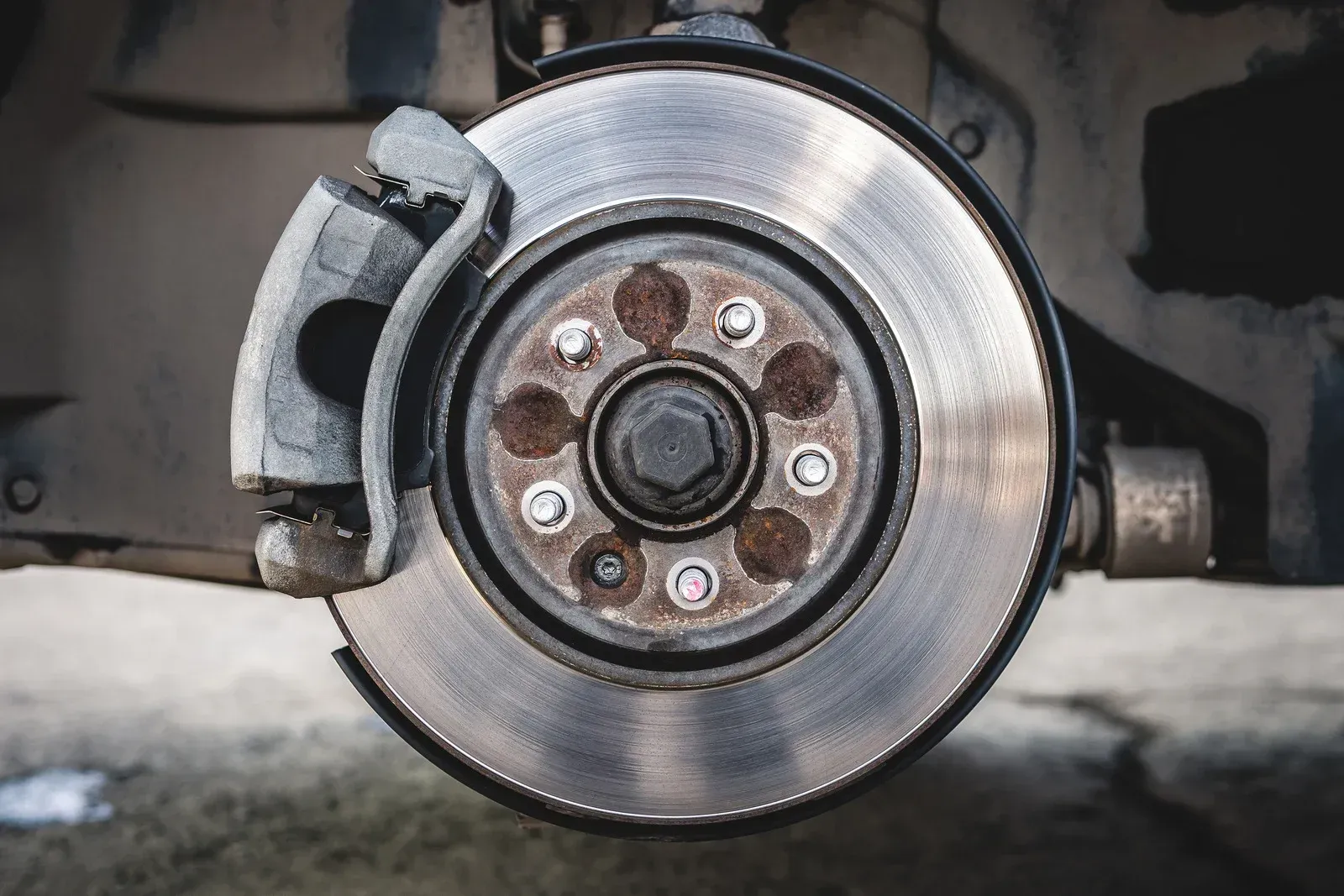 Close-up of a car brake rotor and caliper with wheel removed