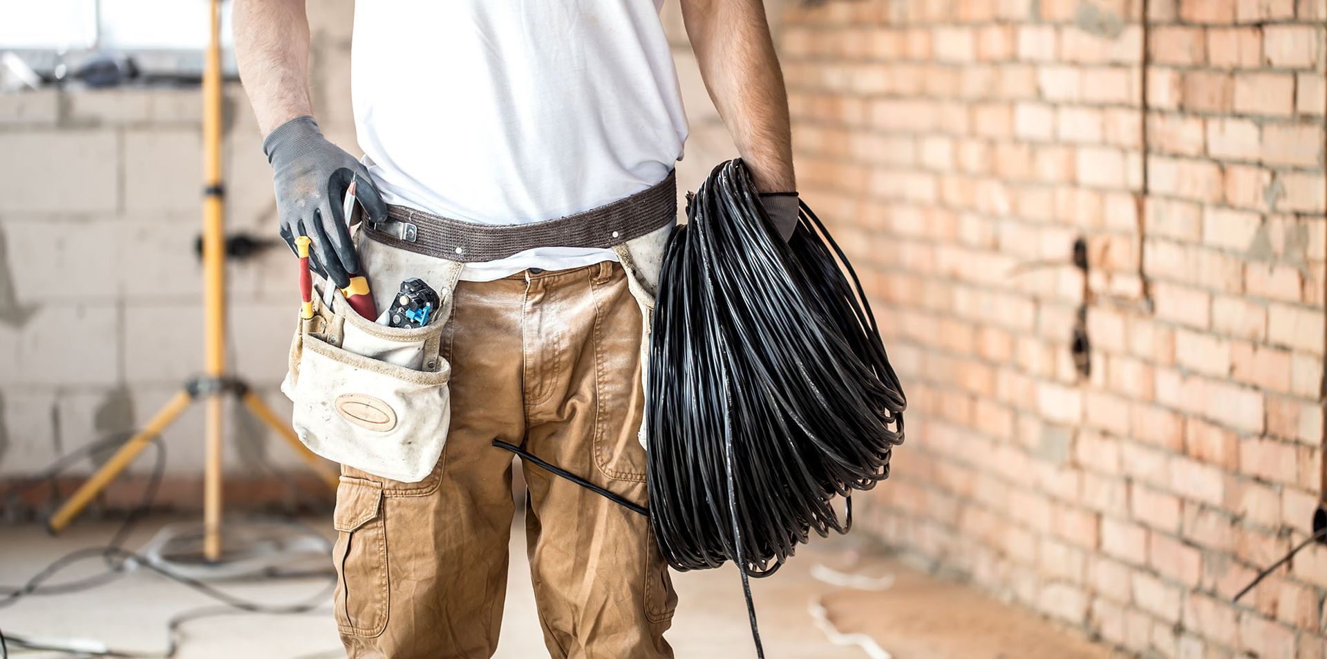 An electrician with tools holding a bunch of wires in his hands