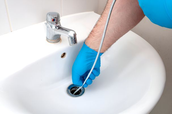 A Person Is Cleaning A Sink With A Hose — Barney Hinds Plumbing In Point Vernon, QLD