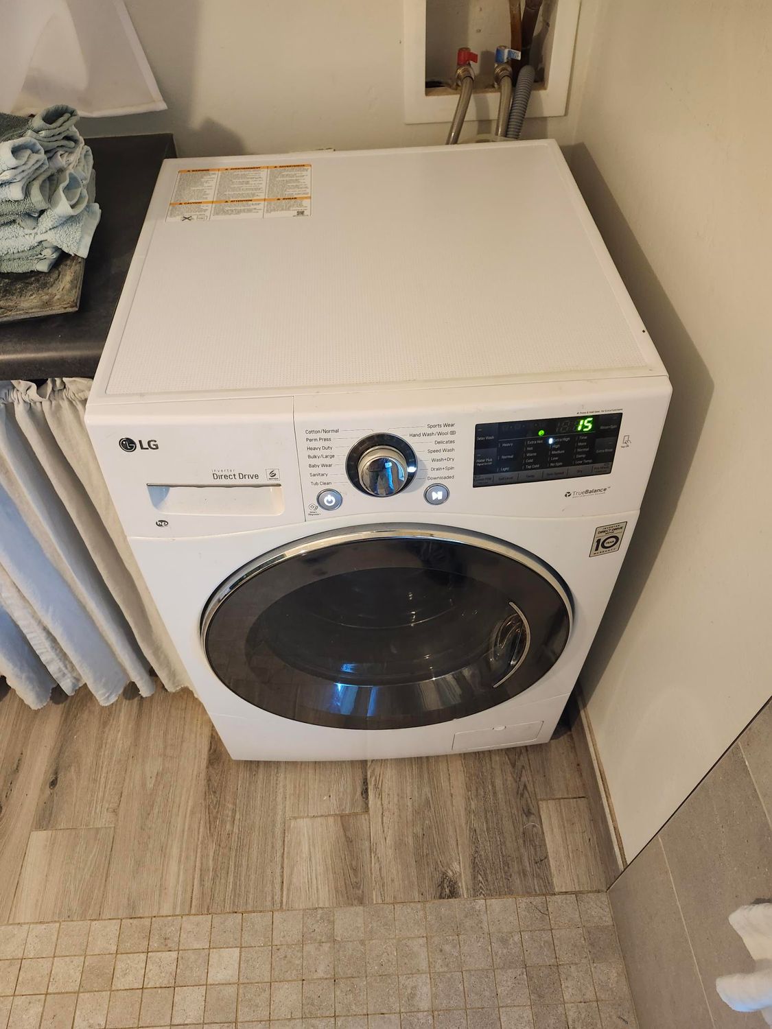 White LG dryer in a laundry room, with a dark door and control panel.