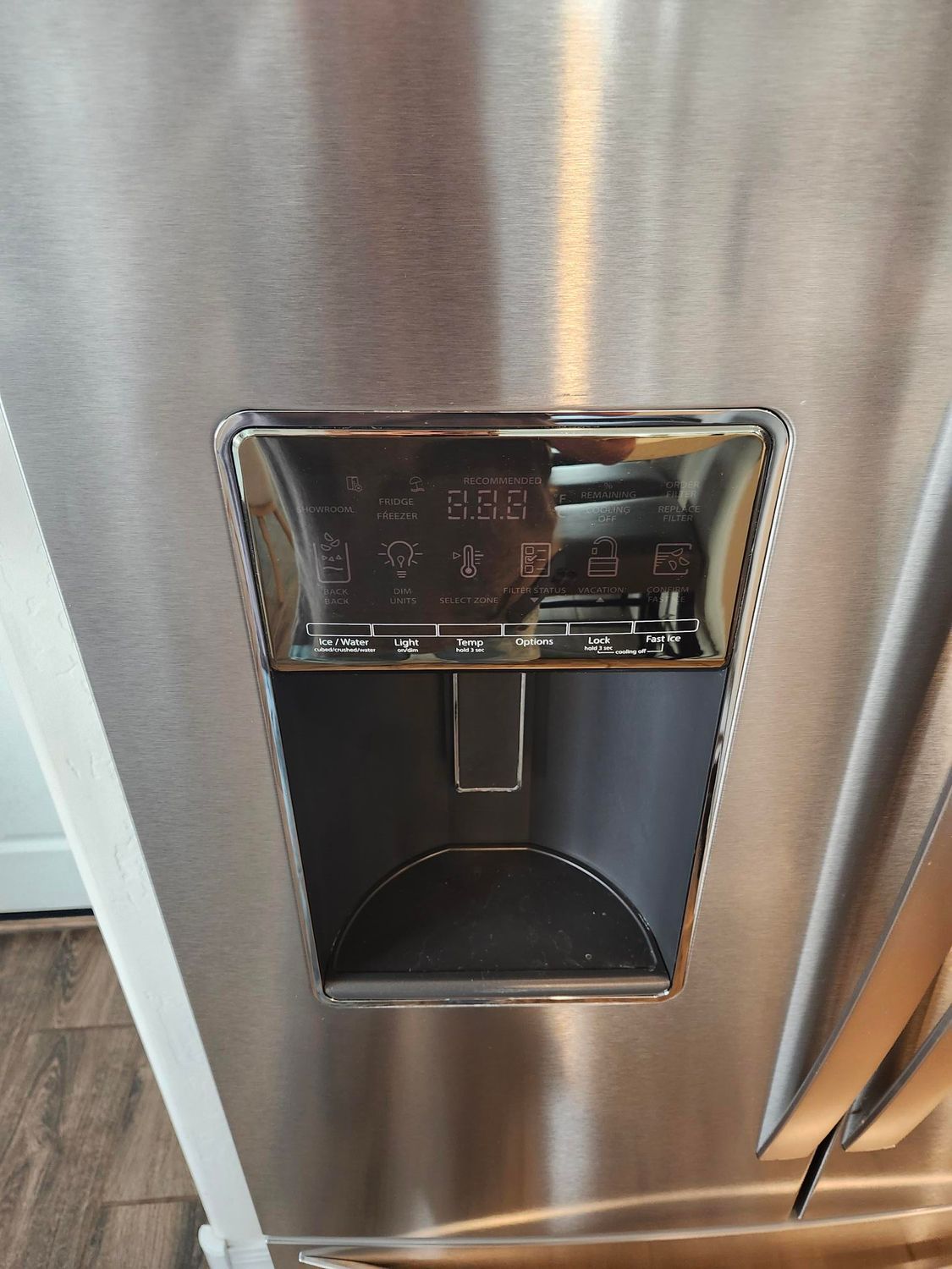 Stainless steel refrigerator water dispenser with control panel.