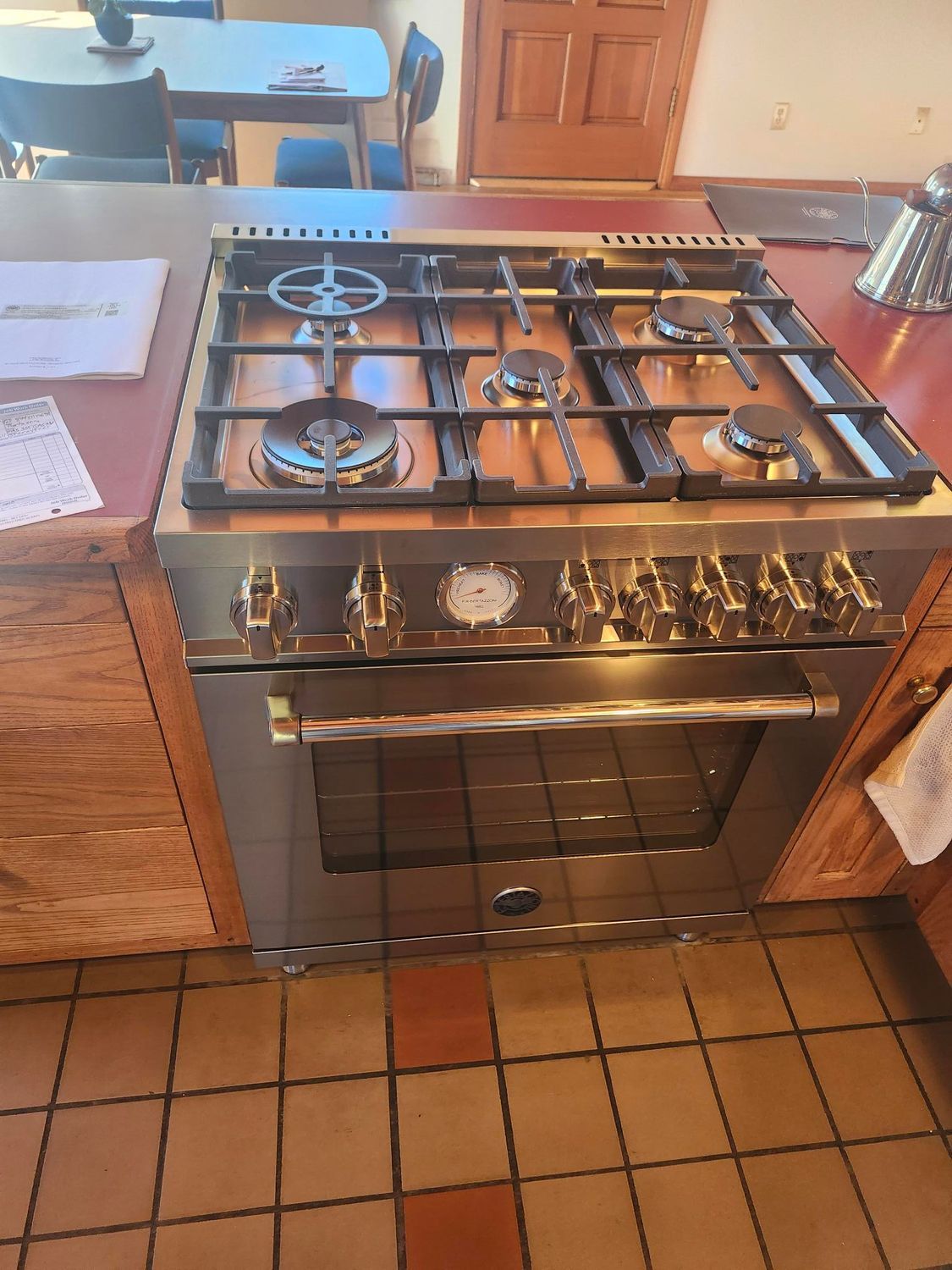 A man is fixing a stove in a kitchen.