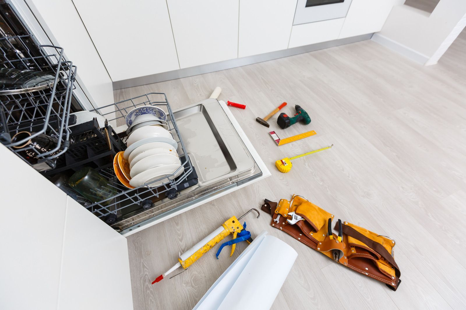 A kitchen with a dishwasher and tools on the floor.