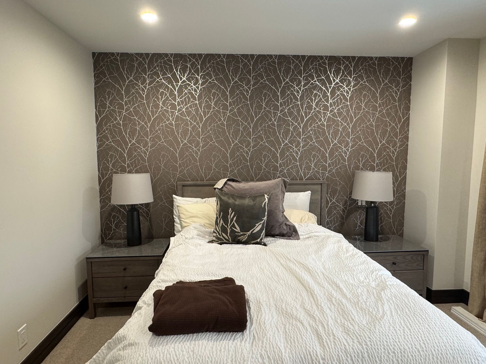 A bedroom with a bed , two nightstands , and two lamps.