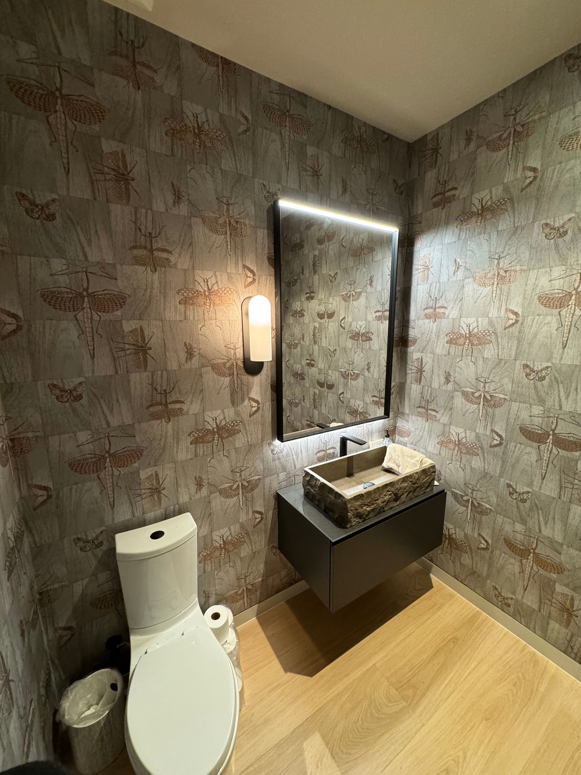 A bathroom with a toilet , sink and mirror.