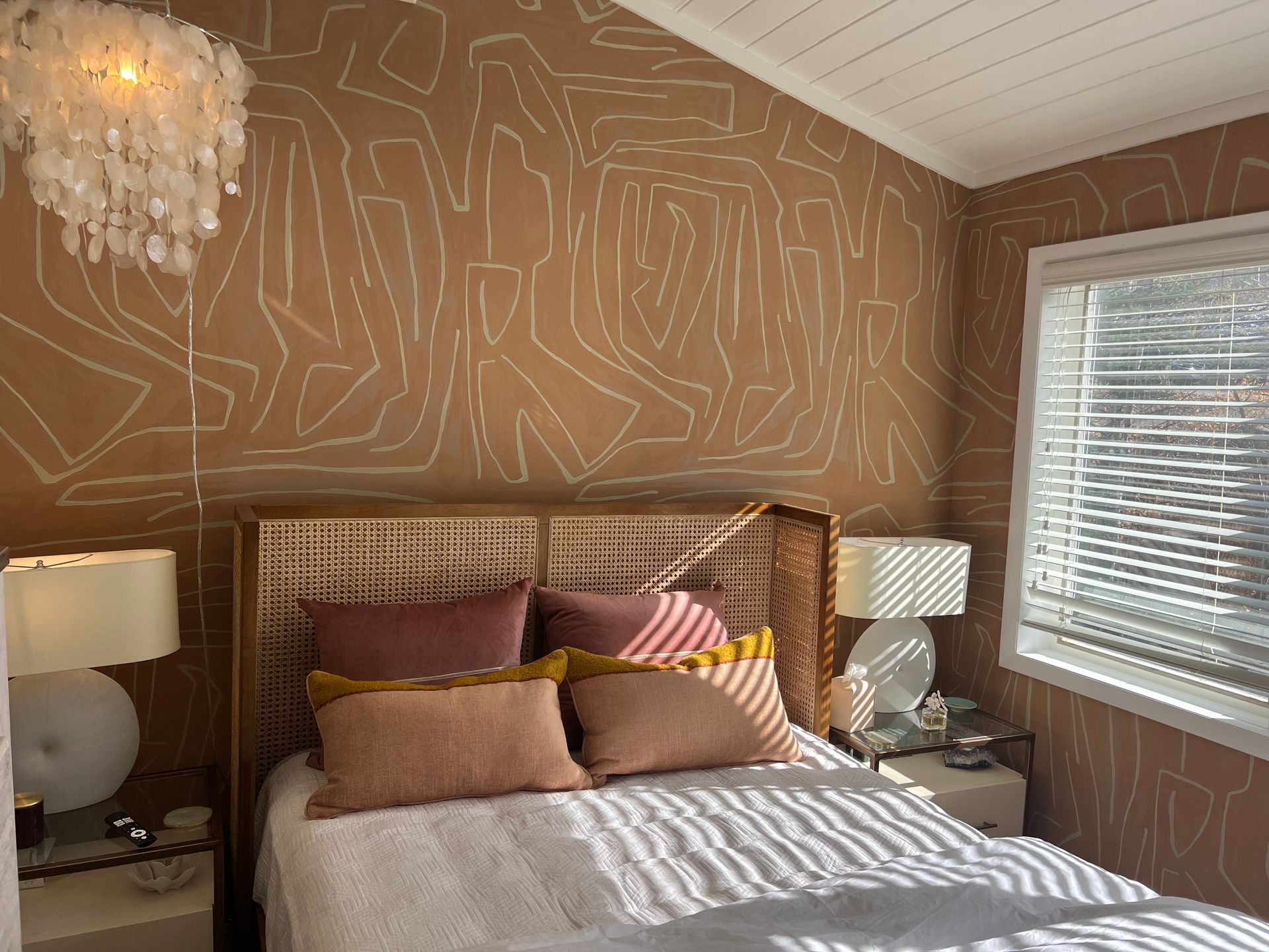 A bedroom with a bed , lamps , and a window with blinds.