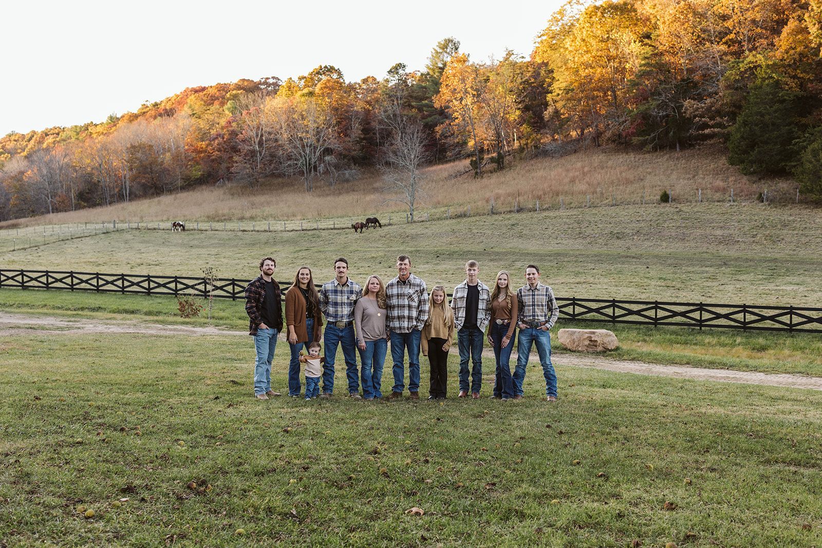 A group of people are standing in a field with a fence in the background.