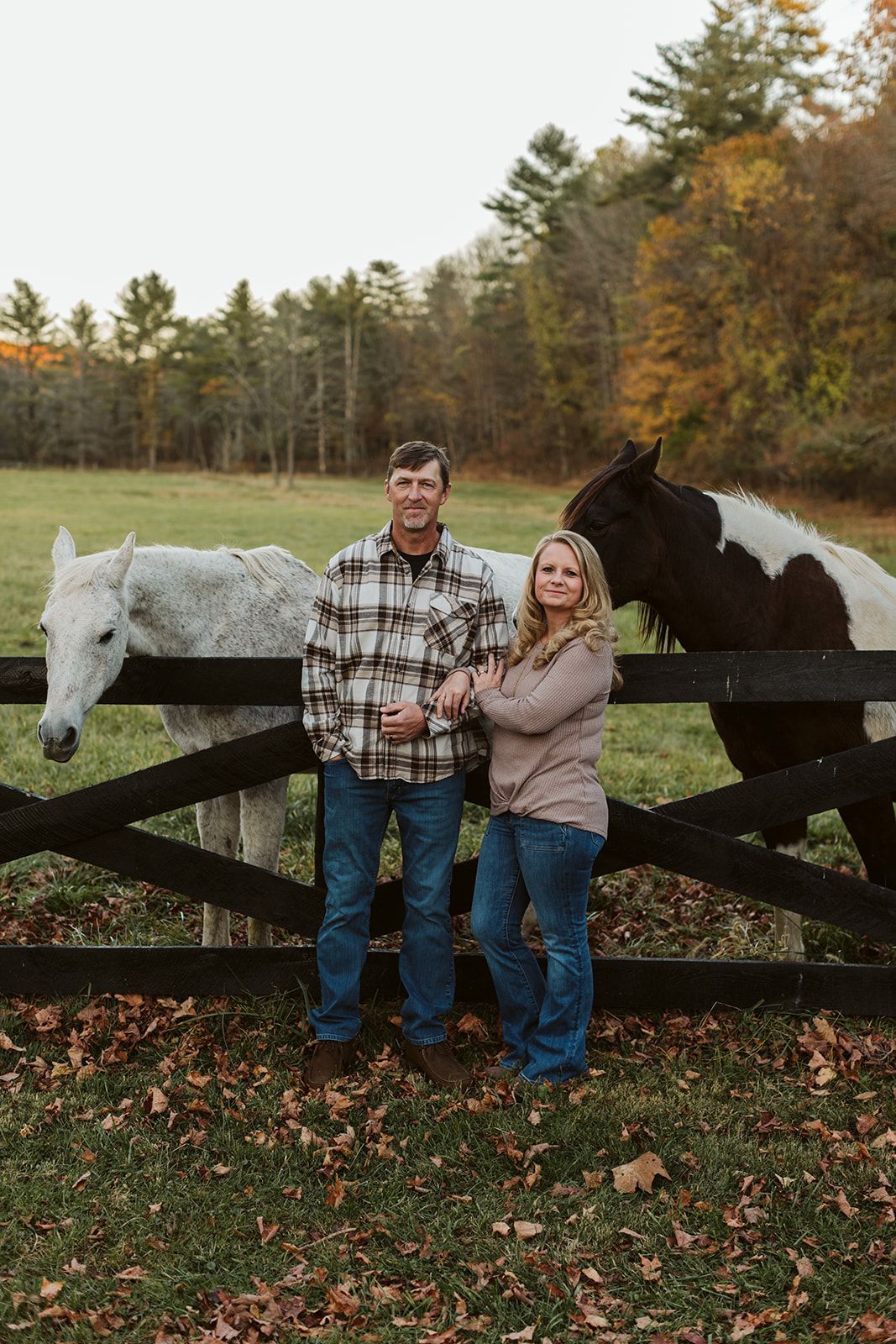 A man and a woman are standing next to two horses in a field.