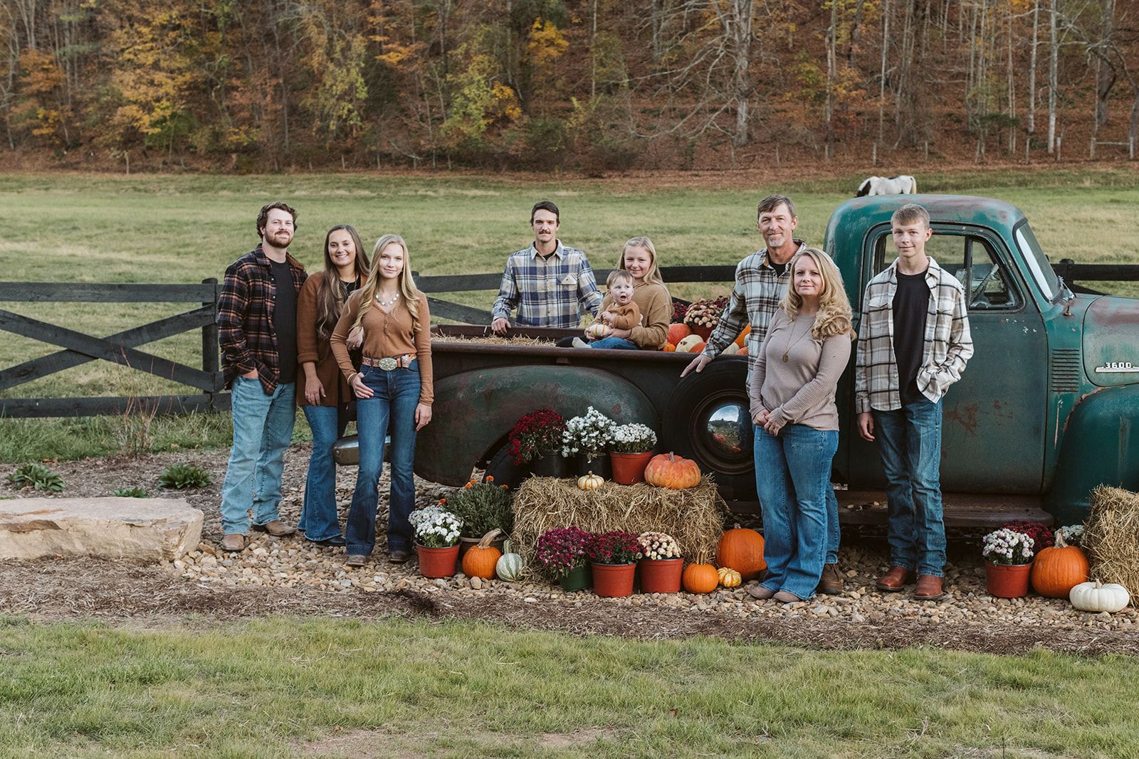 A family is posing for a picture in front of an old truck.