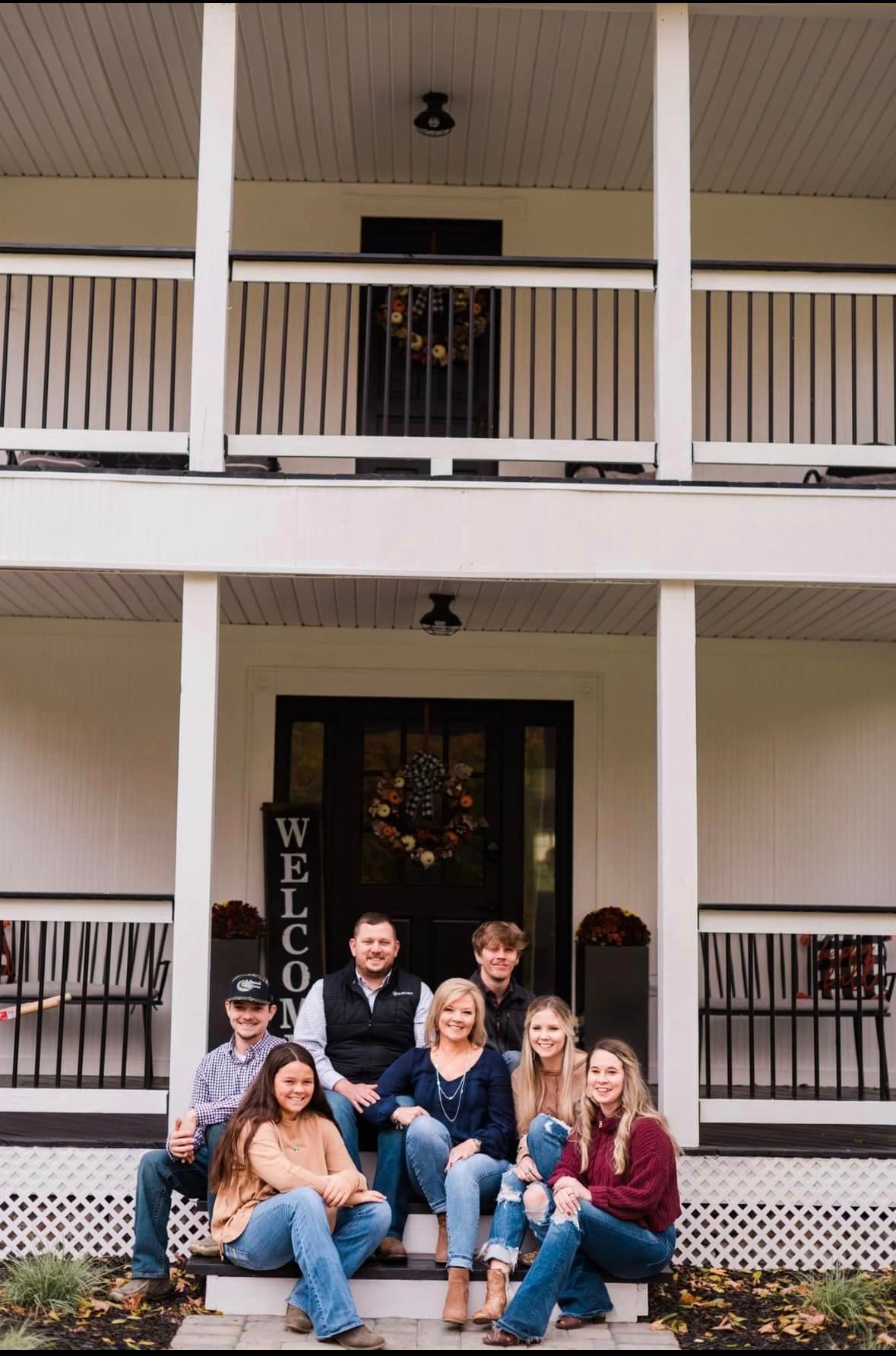 A family is sitting on the steps of a house.