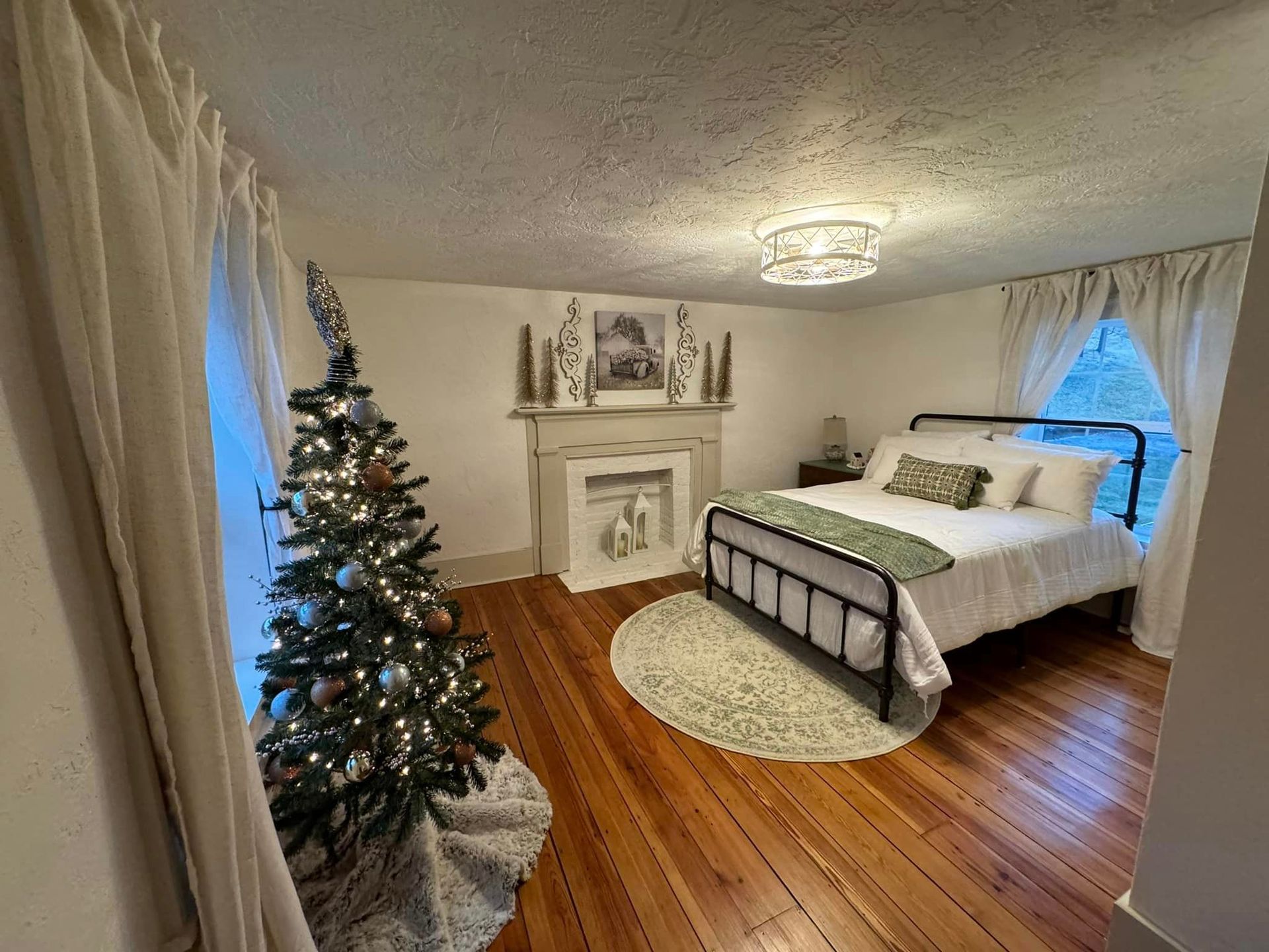 A bedroom with a bed , fireplace and christmas tree.