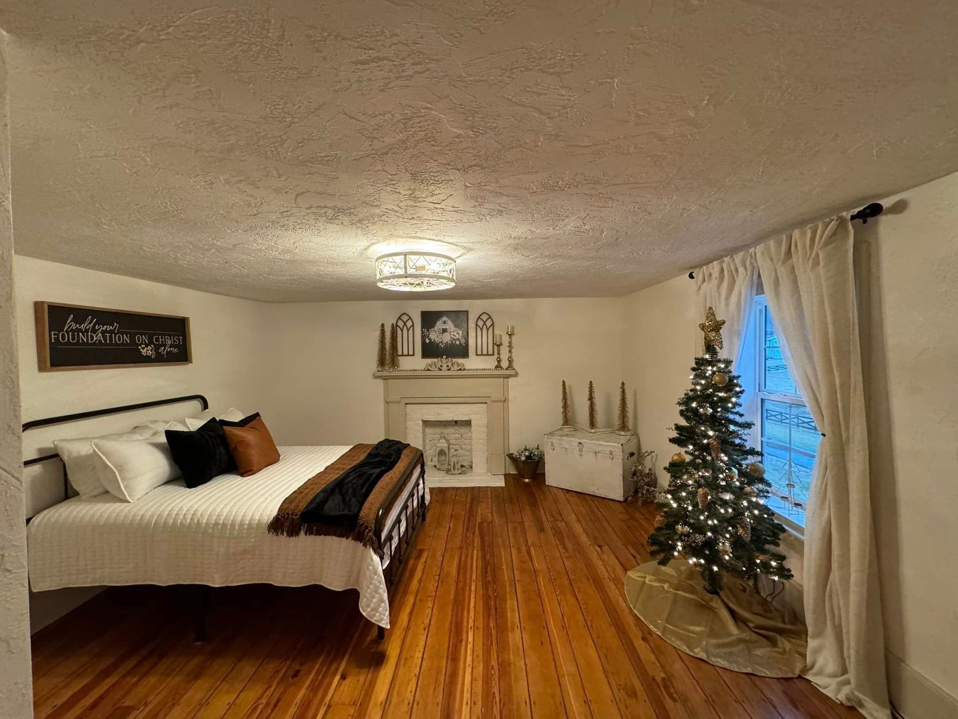 A bedroom with a bed , fireplace , and christmas tree.