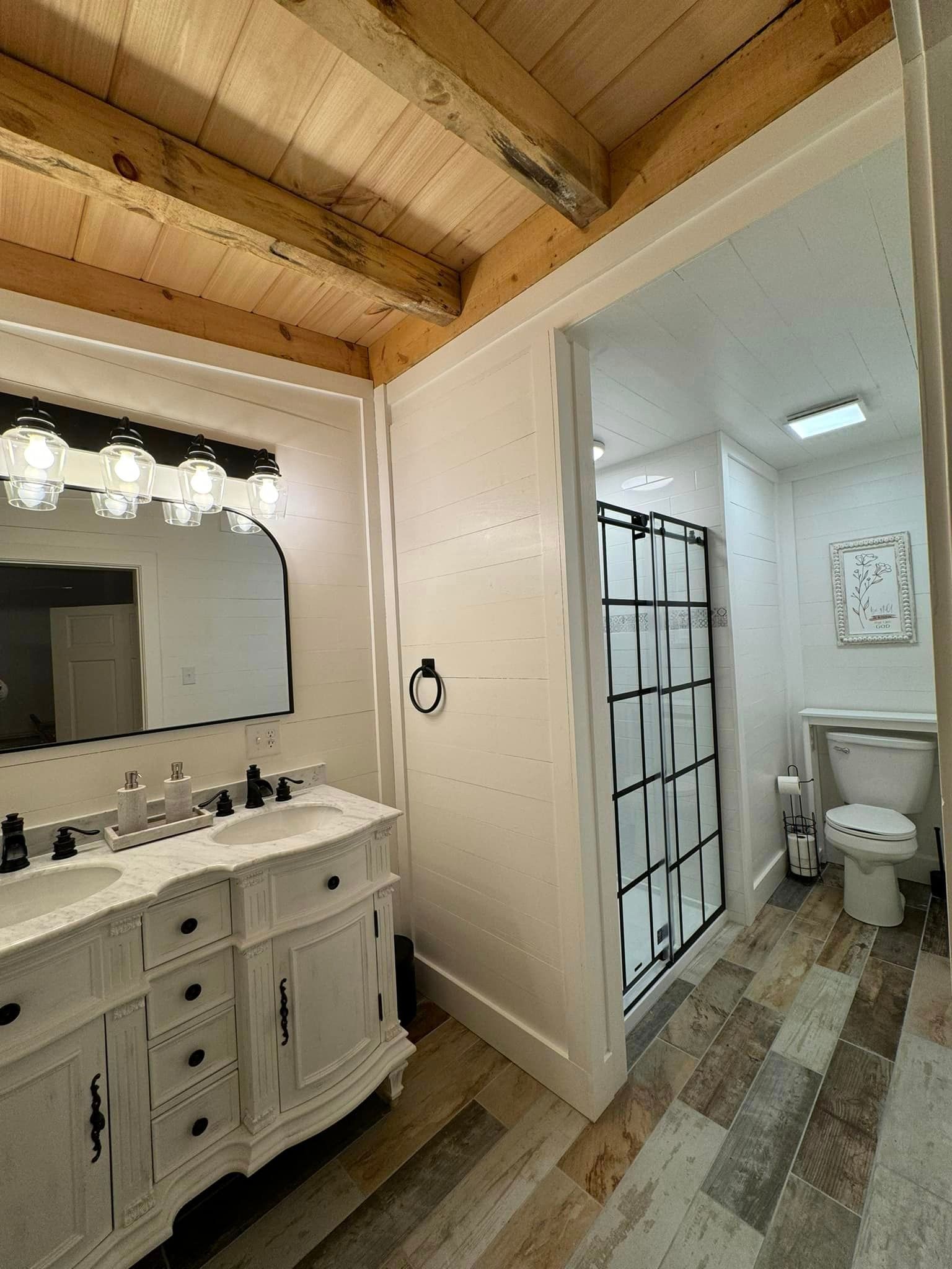 A bathroom with two sinks , a toilet , and a shower stall.