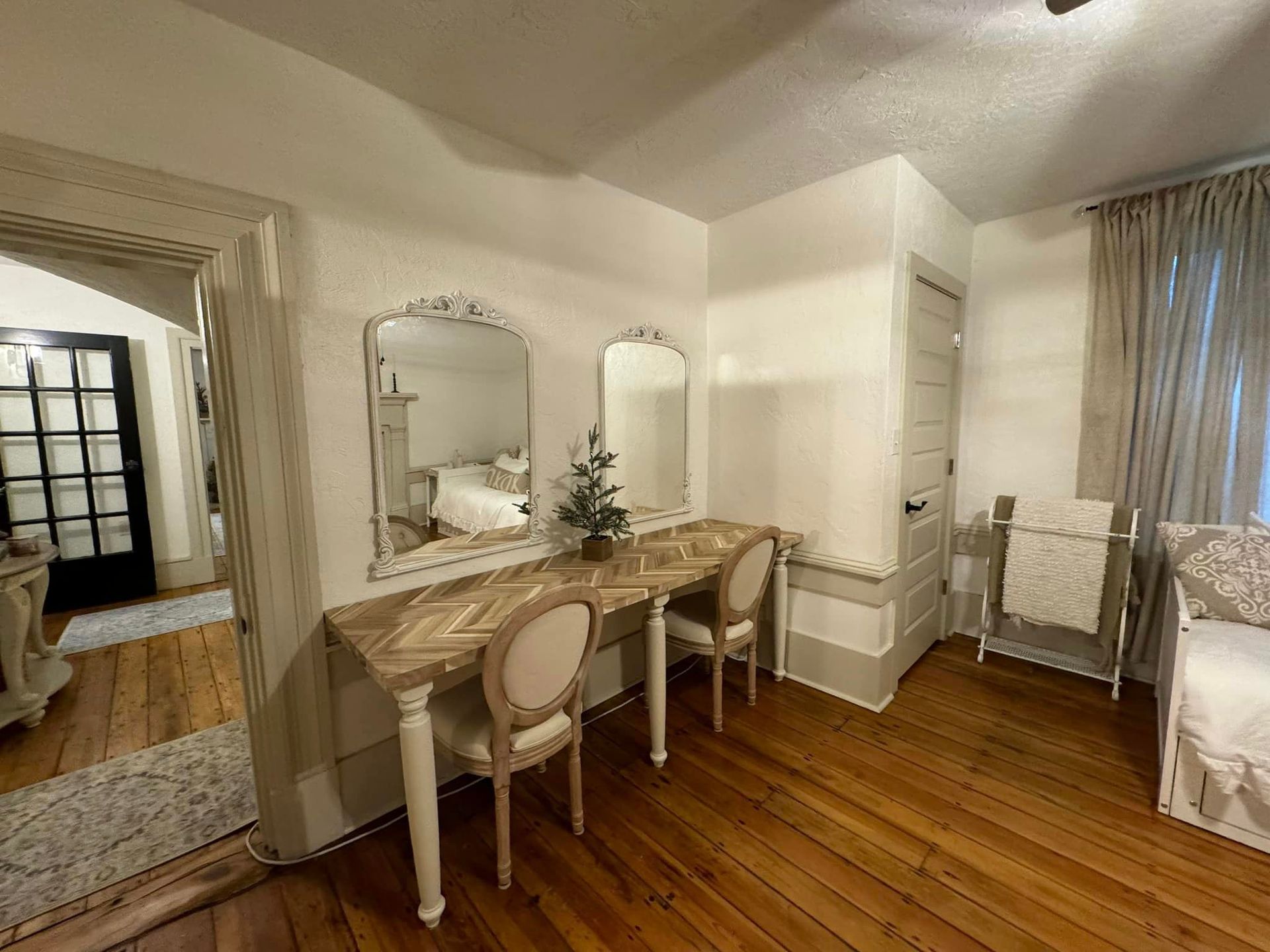 A bedroom with two desks and two mirrors on the wall.