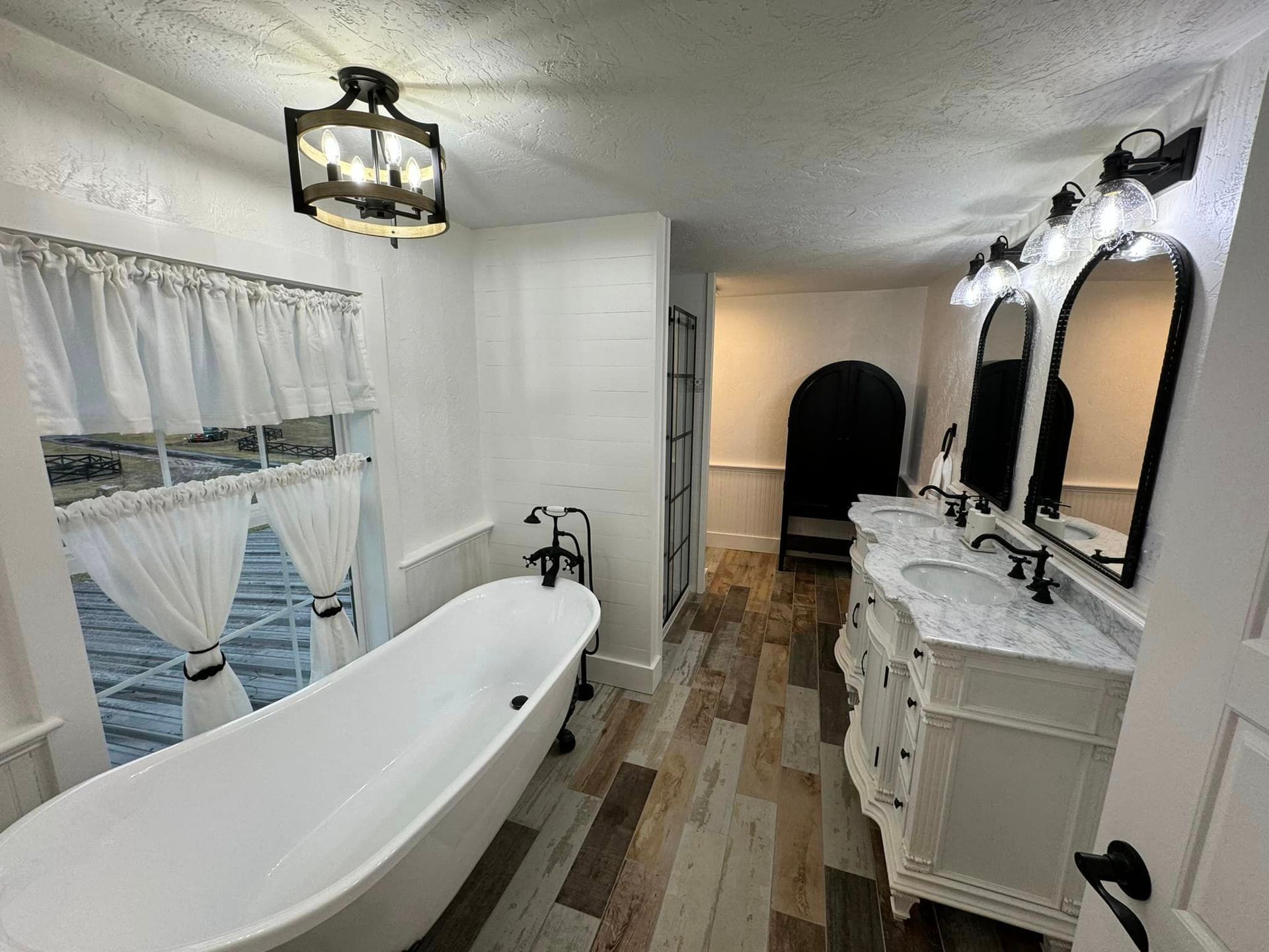 A bathroom with a bathtub , sinks , mirrors and a window.