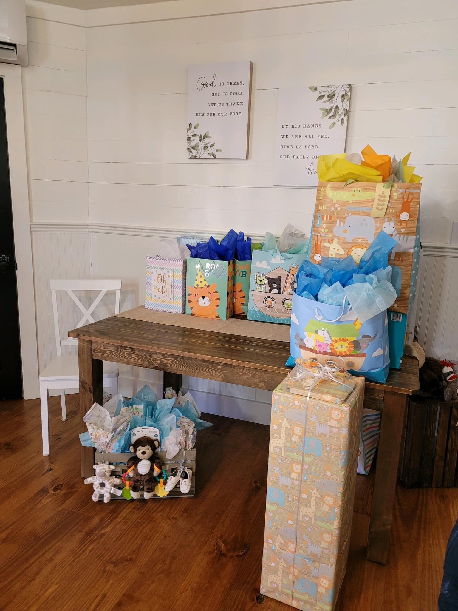 A wooden table filled with lots of gifts for a baby shower.