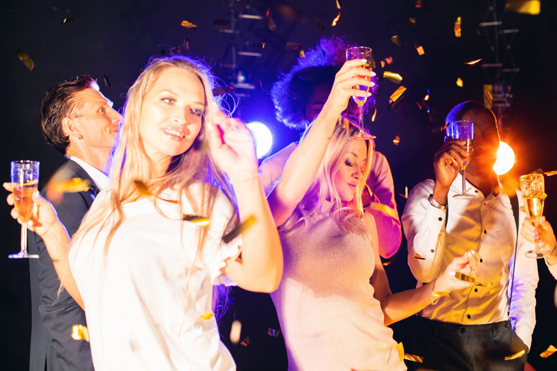 A group of people are dancing and drinking champagne at a party.