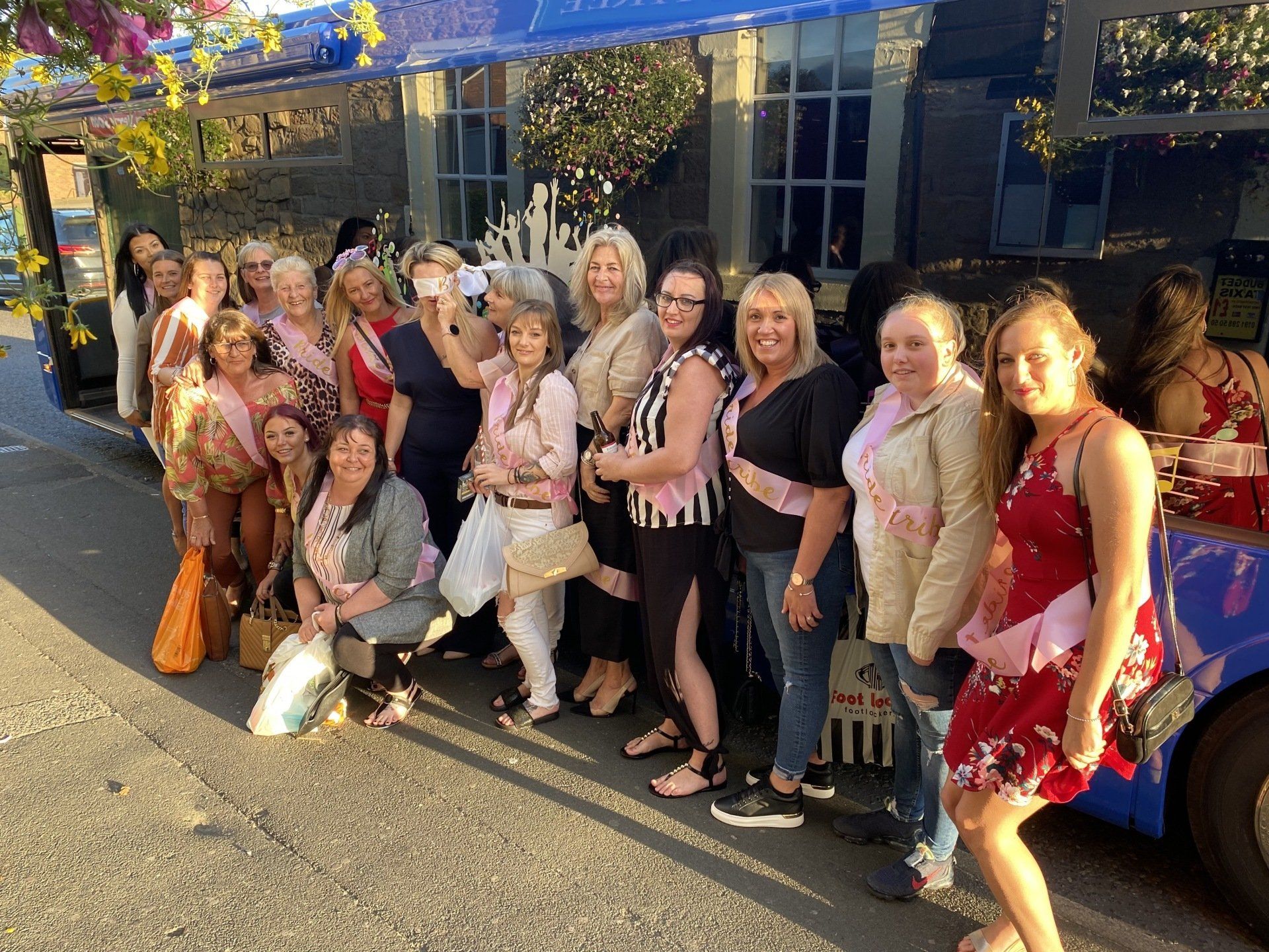 A group of women are posing for a picture in front of a bus.