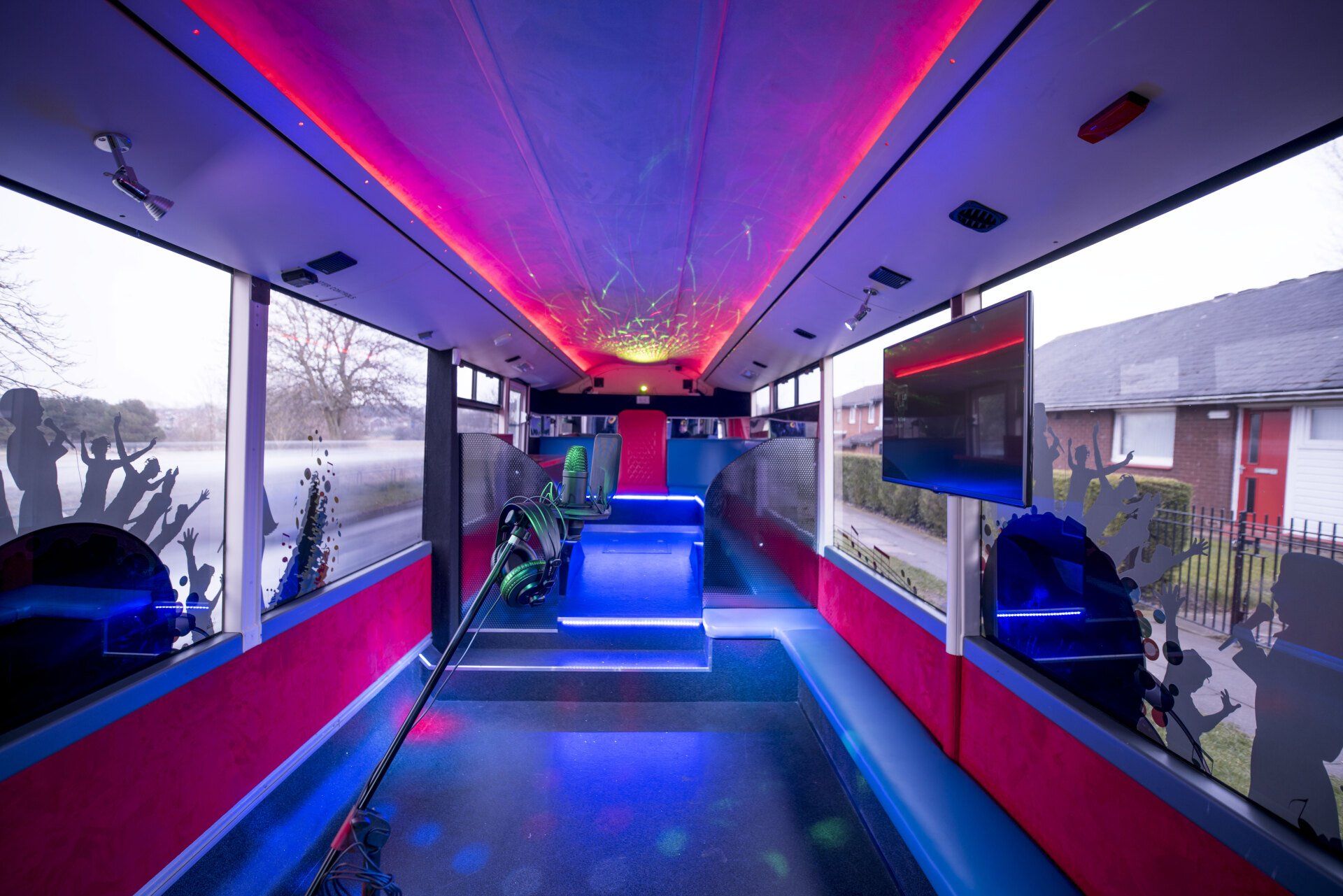 The inside of a bus with purple lights on the ceiling