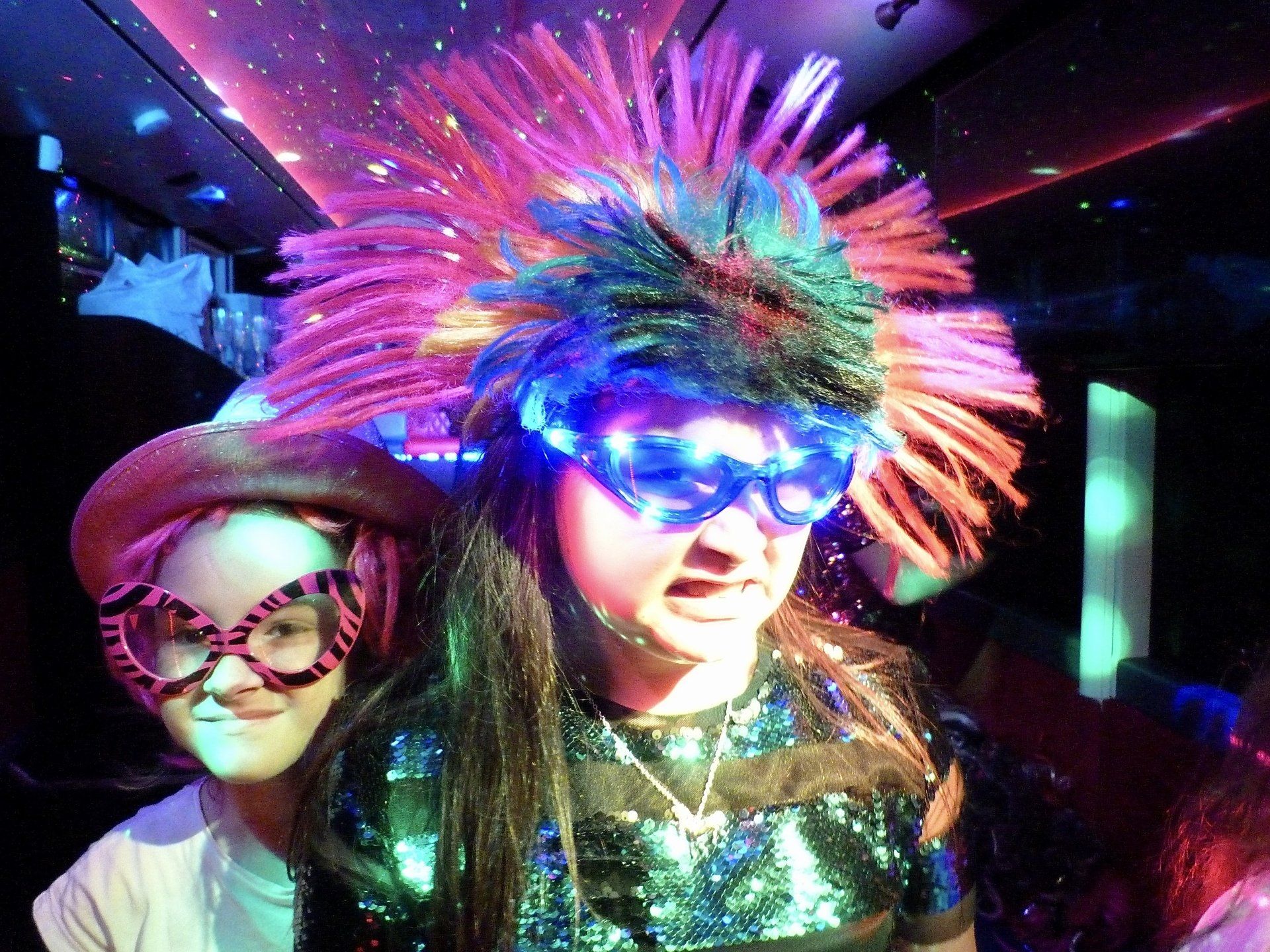 A girl wearing glasses and a hat with feathers on it