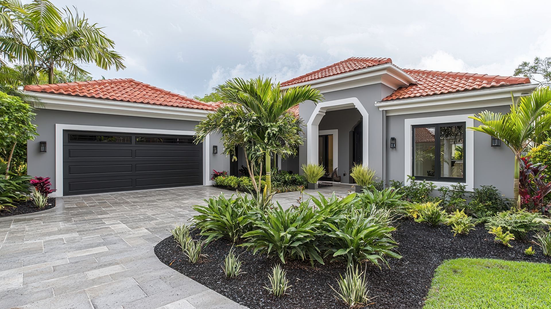 A large house with a black garage door and a red tile roof.