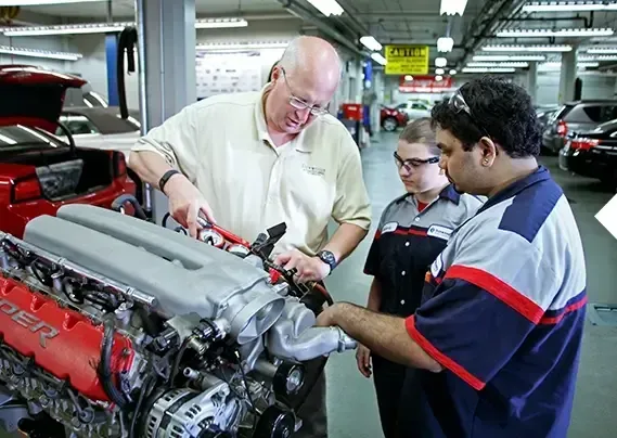 Three men are working on a car engine in a garage.