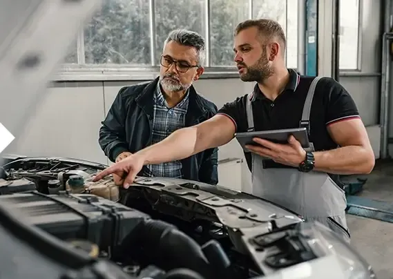 Two men are looking under the hood of a car.