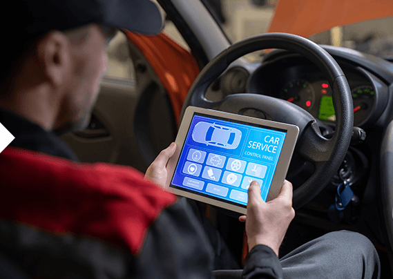 A man is sitting in a car using a tablet.