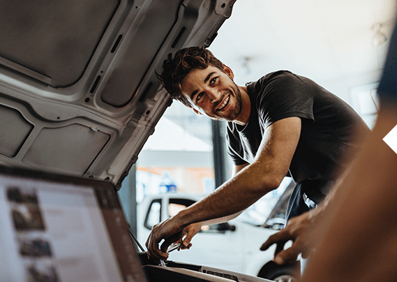A man is working on the engine of a car in a garage.