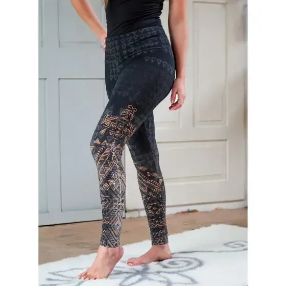 Eine Frau steht in schwarzen Leggings auf einer Yogamatte
