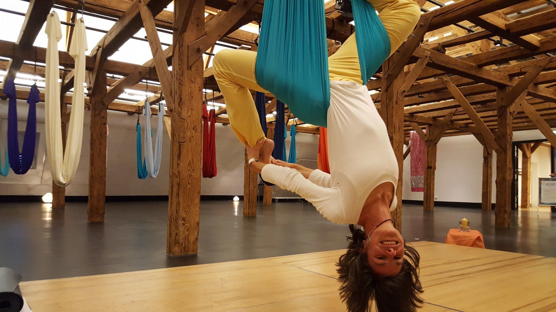 Eine Frau hängt kopfüber in einer Yoga-Hängematte.