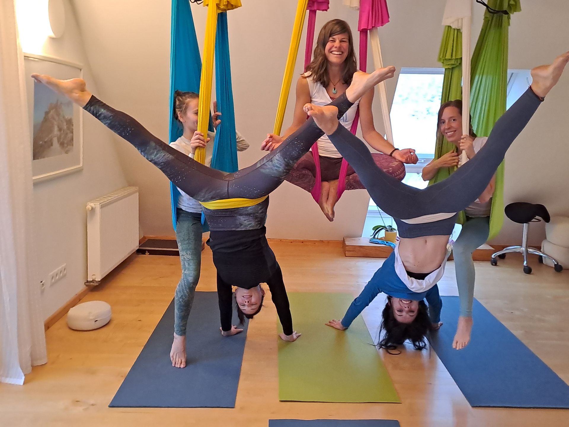 Eine Gruppe von Menschen macht in einem Raum Aerial Yoga.