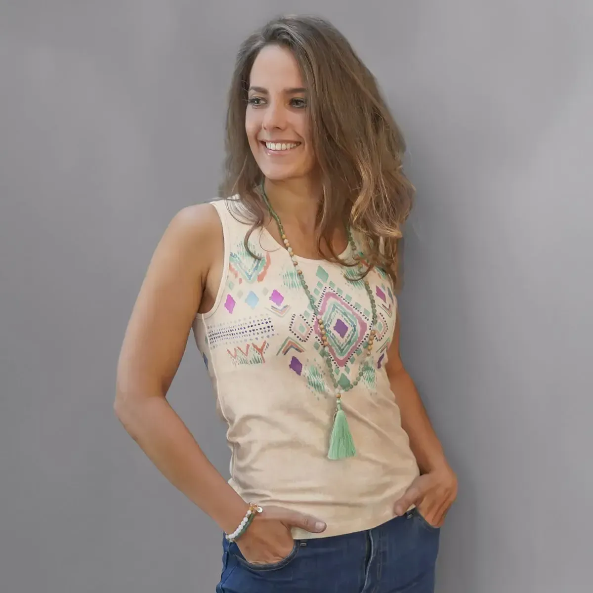 Eine Frau in einem Tanktop und einer Halskette lächelt