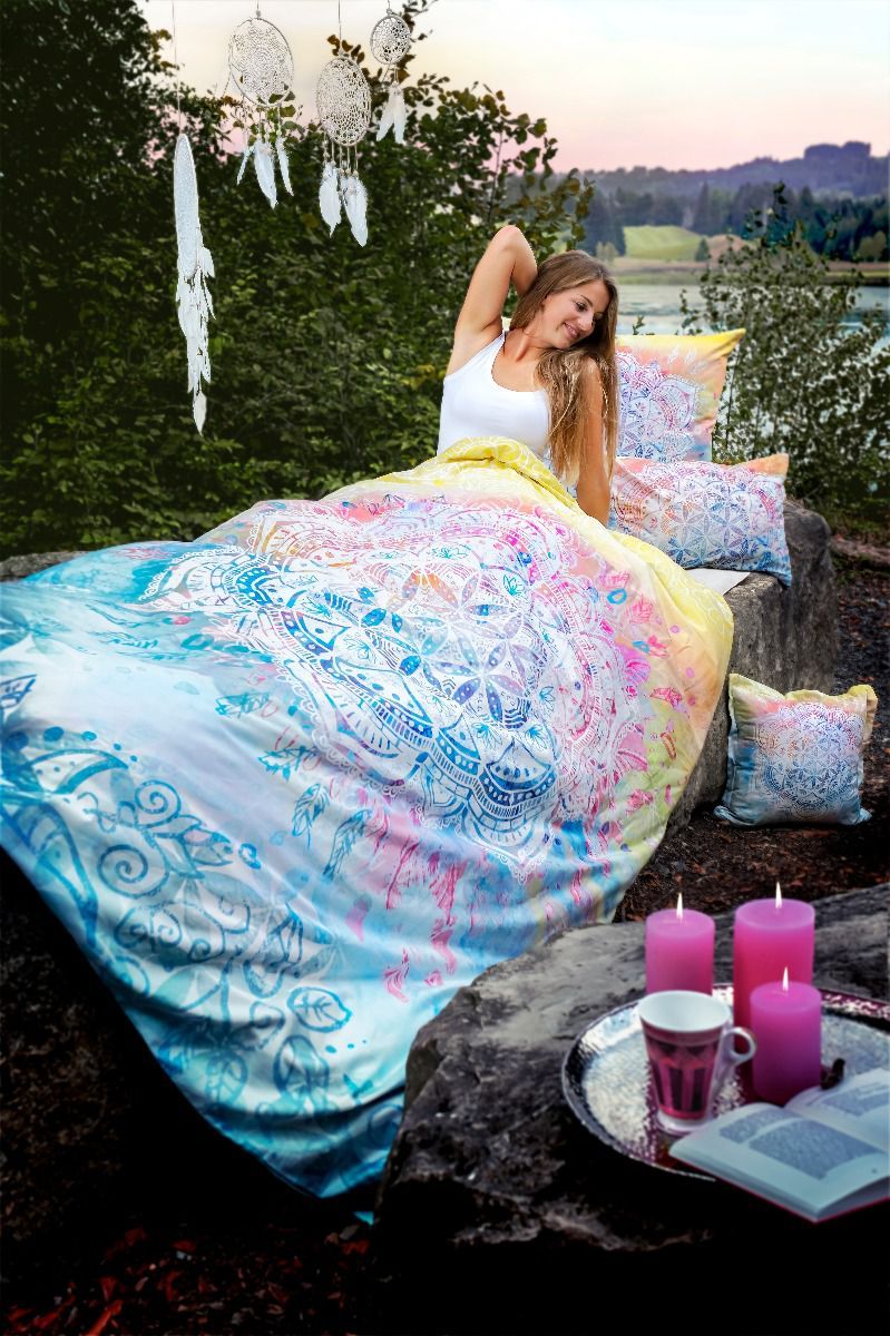 Eine Frau liegt auf einem Bett mit einer bunten Bettdecke und Kissen.