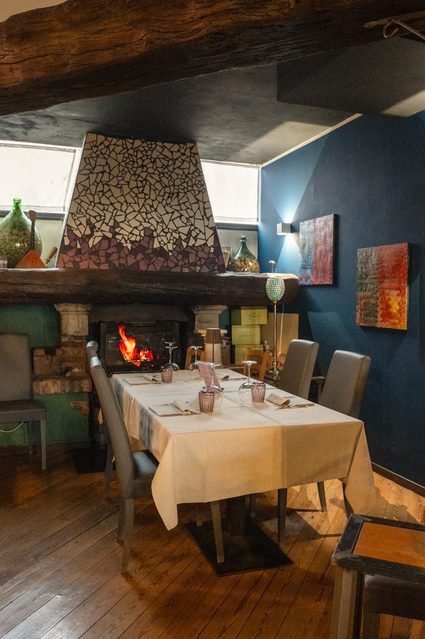 Interno del bar con sedute in pelle nera, tavoli rotondi, mobili in legno e grandi piante.