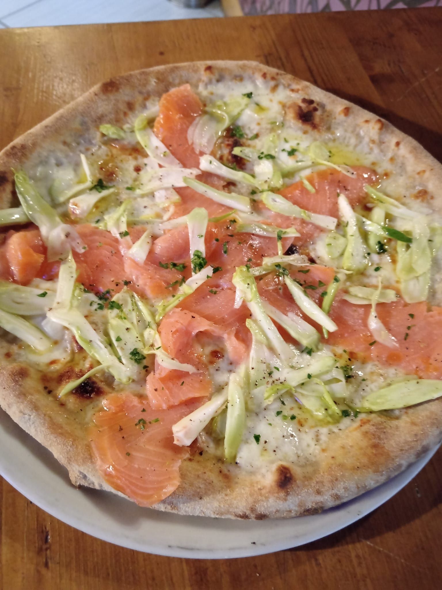 Interno del bar con tavoli e sedie in legno, ampia finestra con vista sul verde esterno.