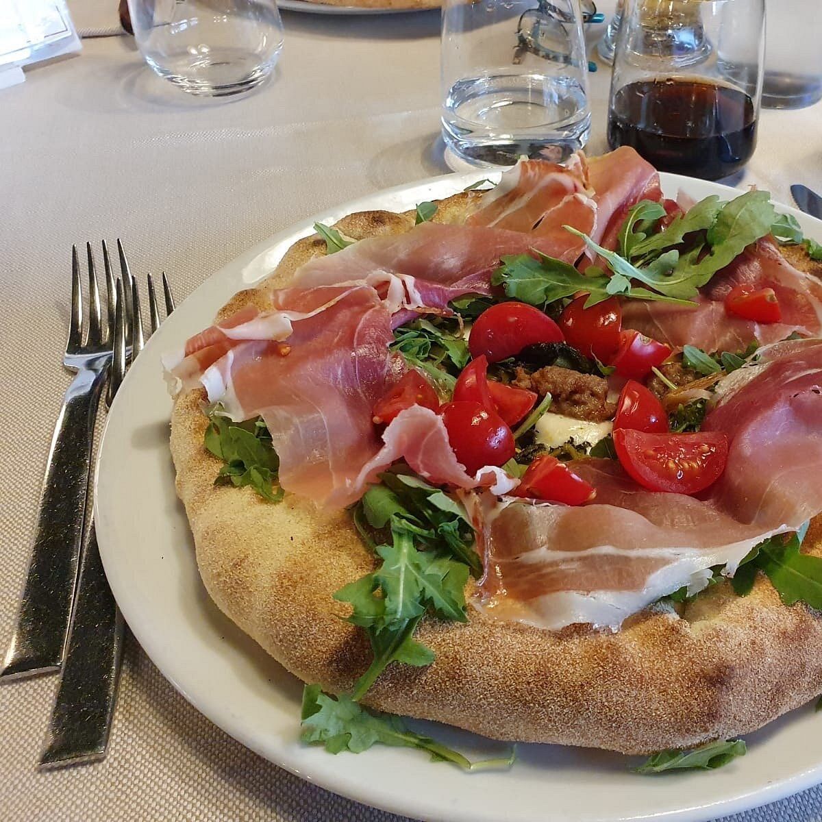 Caffetteria interna con sedute in pelle nera, tavoli in legno e ampie finestre con vista sul verde.