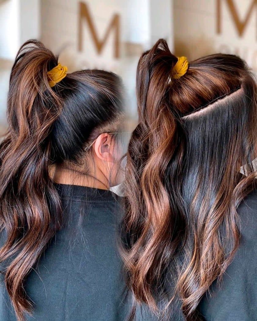 Two women with dark, wavy hair in half-up ponytails, one with a diagonal side part, both with gold scrunchies.