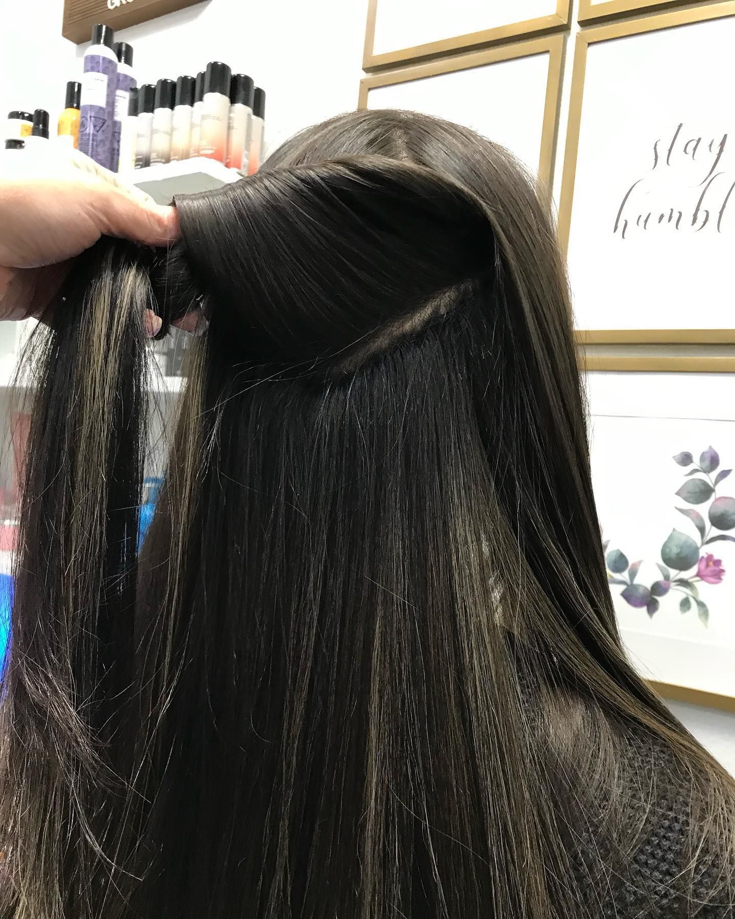 Close-up of hair being styled.  A hand holds the hair up, revealing a sectioned area, likely for a braid.
