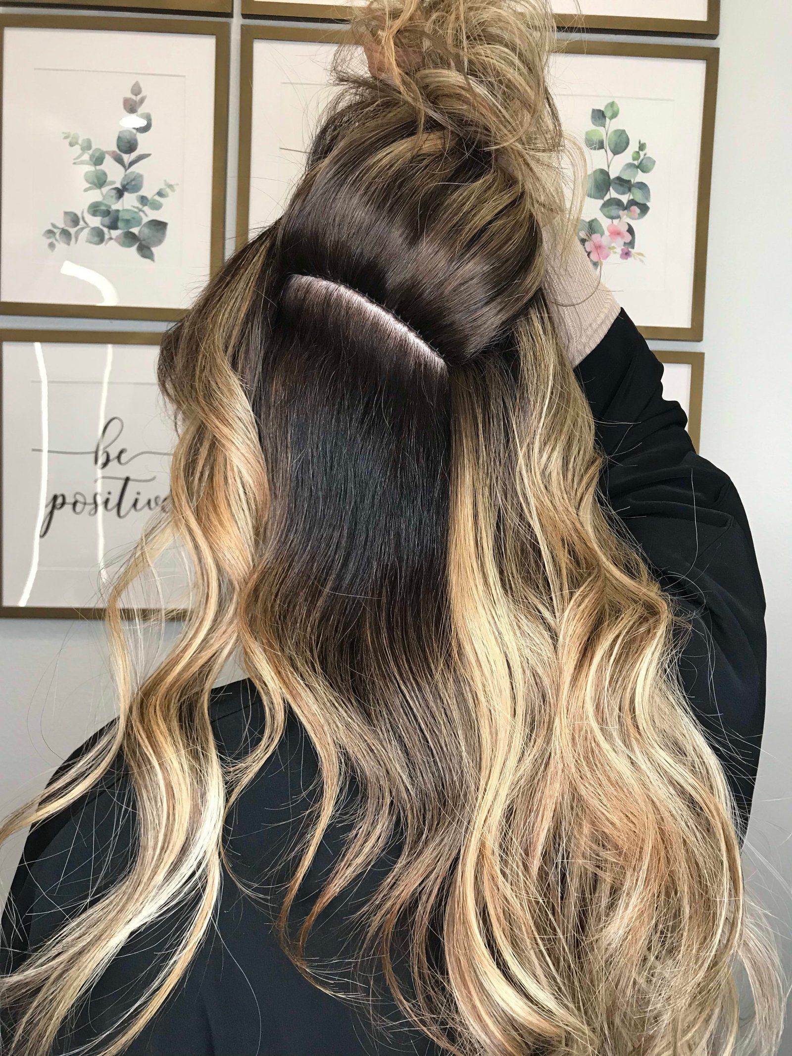 Person with blonde hair; dark roots showing, some hair up, some down.