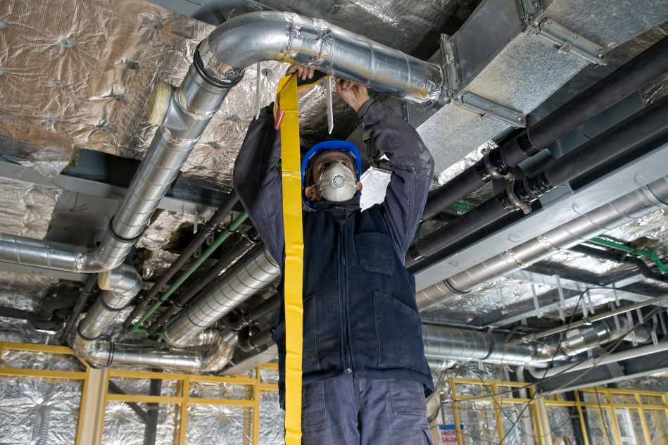 A man is standing in front of a bunch of pipes and valves.